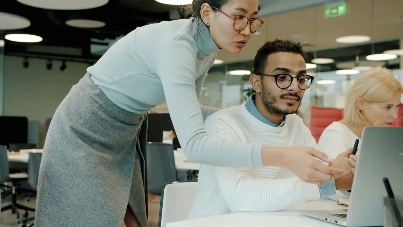 Two colleagues reviewing work together on a laptop in a modern office